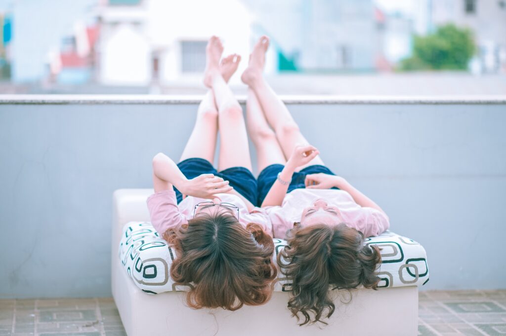 Twin girls relaxing on sofa with feet up