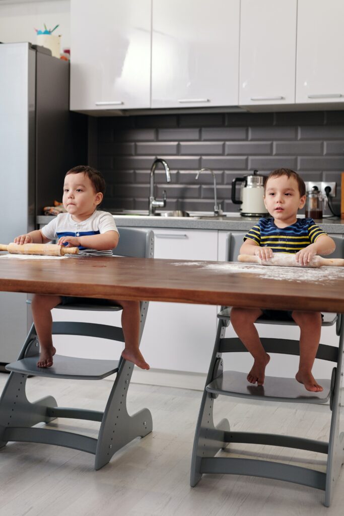 Twin boys sitting in high chairs in kitchen