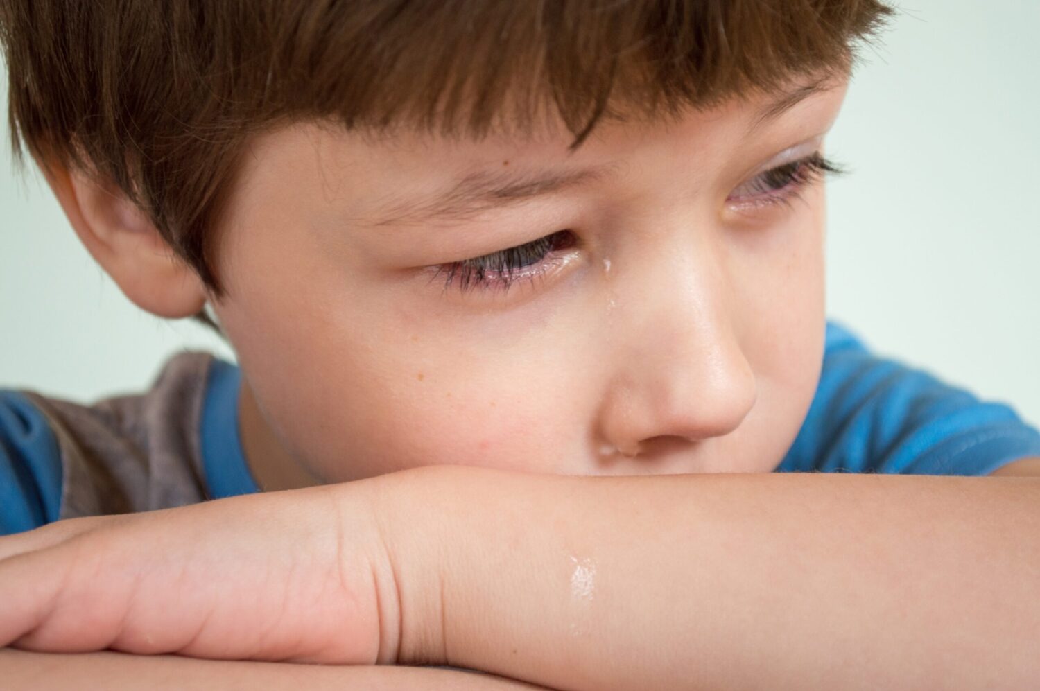 Boy laying his head on his arm and crying