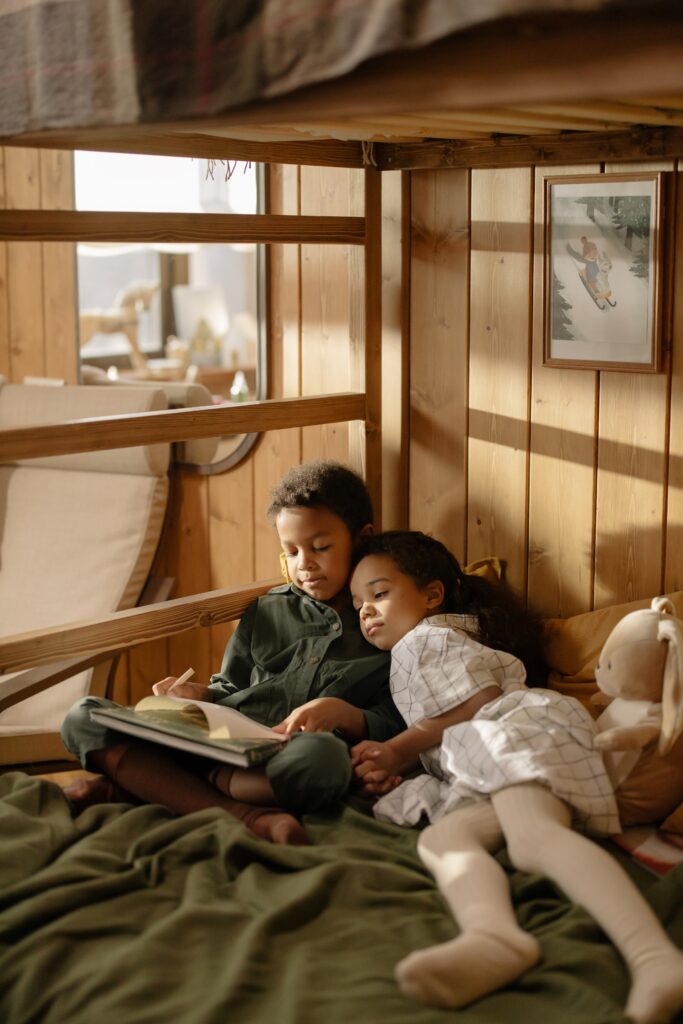 Boy and girl twins on bed looking at book